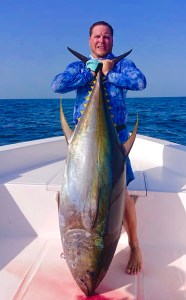 Angler holding a yellowfin tuna vertically on a boat, caught on a Hamachi rod
