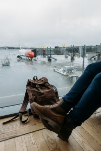 Angler waiting at the departure gate with travel bag watching the plane board