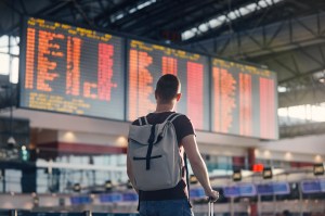 Angler with carry-on bag checking the departures board before a fishing trip