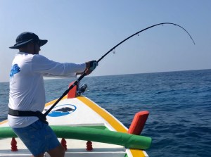 Angler fighting a tuna on a Hamachi rod from a traditional outrigger boat in the Indian Ocean