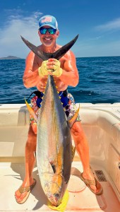 Angler holding a large yellowfin tuna vertically on a boat in Panama